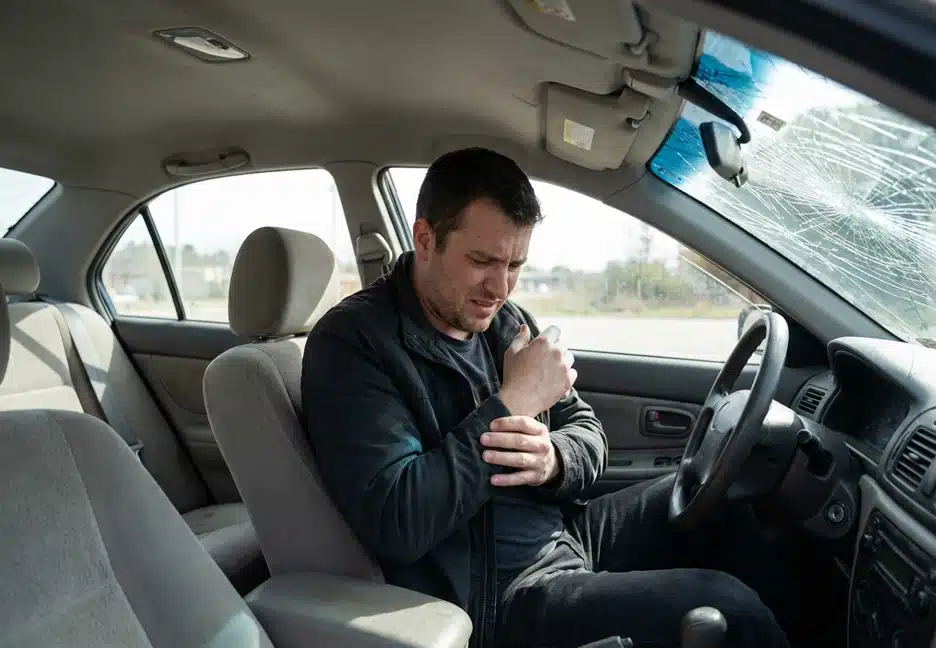 man holding his arm in pain from a car accident