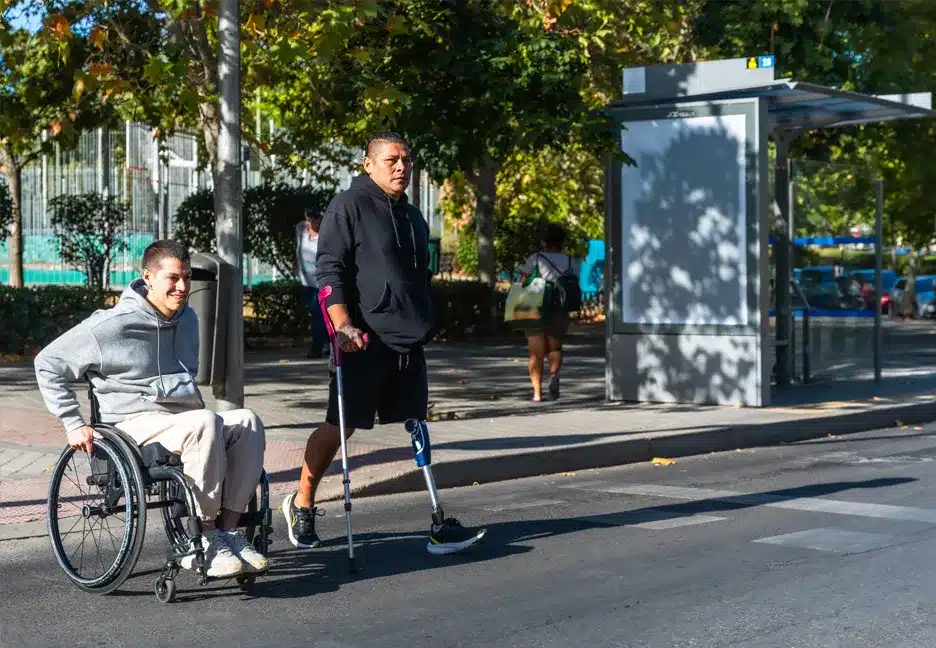 guy in a wheelchair and guy on crutches walking in the street