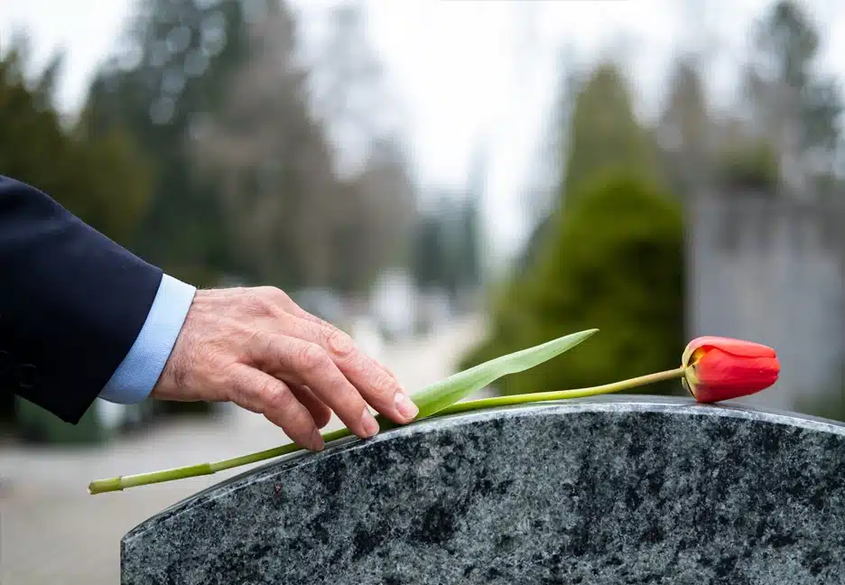 man putting rose on head stone